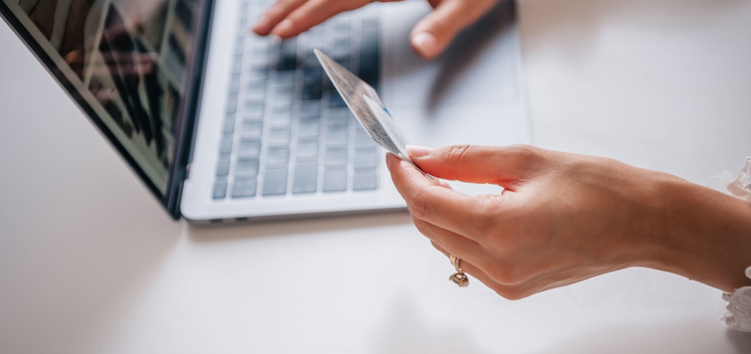Persoon voert online betaling uit op laptop en houdt bankpas in de hand.
