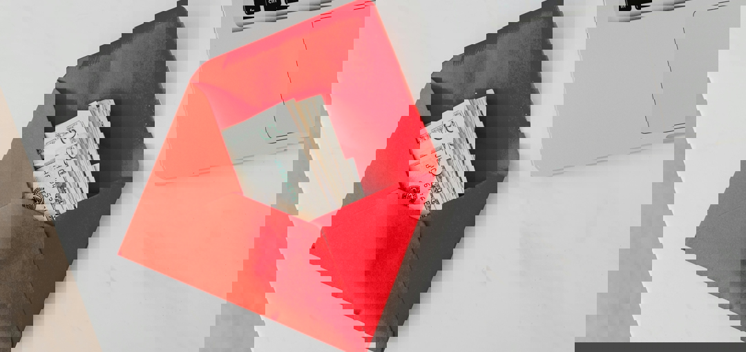 Een laptop op tafel met een envelop vol geld