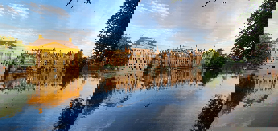 Imposant gebouw van het Binnenhof in Den Haag, met een ruime vijver aan de voorkant.